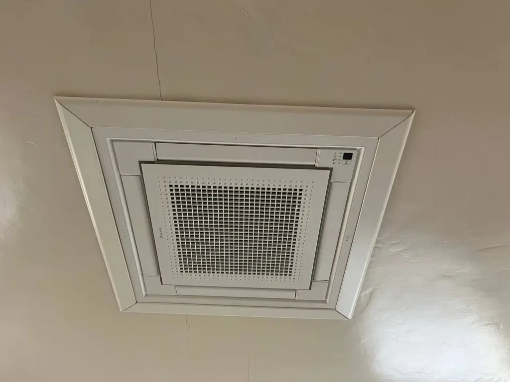 Top-rated technician installing a ductless ceiling cassette air conditioning unit in a Sacramento home. The sleek, modern unit is being carefully aligned and secured into the ceiling space, ensuring all connections to the home’s cooling system are properly made, enhancing comfort in Sacramento’s unique climate.