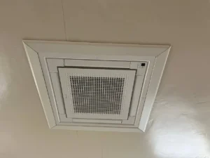 Top-rated technician installing a ductless ceiling cassette air conditioning unit in a Sacramento home. The sleek, modern unit is being carefully aligned and secured into the ceiling space, ensuring all connections to the home’s cooling system are properly made, enhancing comfort in Sacramento’s unique climate.